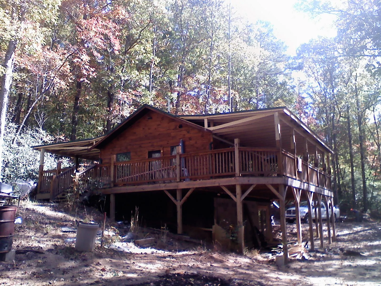 Log cabin with a wraparound porch and metal roof in the fall in Hudson